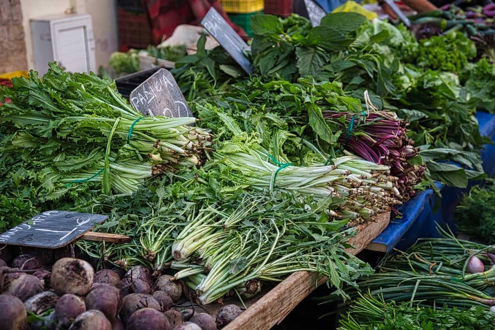 Stall full of fresh spring leafy vegetables on farmers market in Greece