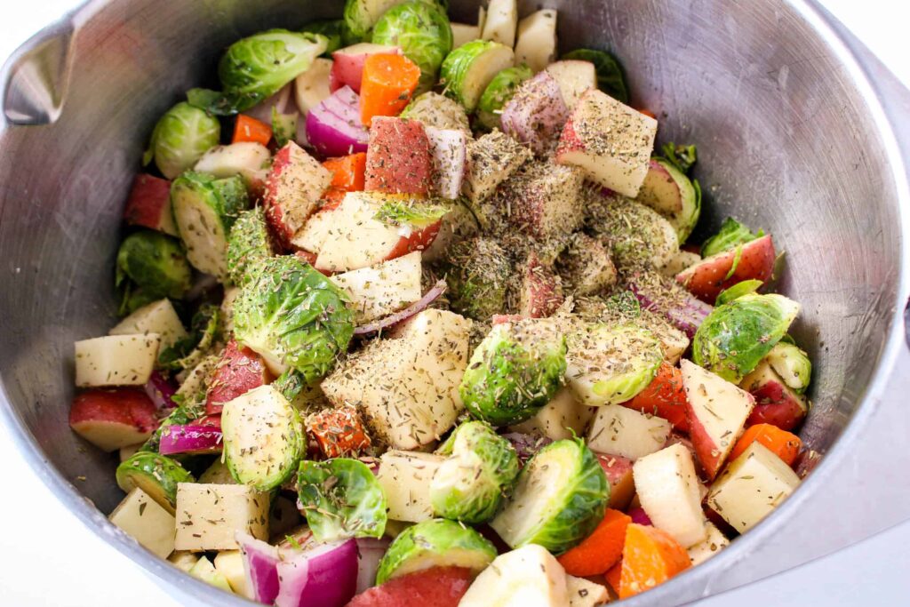 Brussels sprouts, carrots and potatoes in a bowl, sprinkled with herbs.